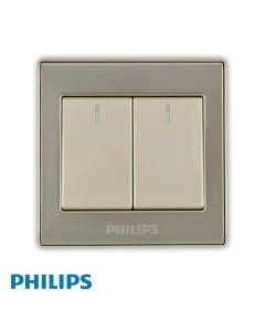 Philips two-switch light switch plate in a warm beige finish with a matching metallic frame, shown on a white background with a blue Philips logo watermark at the bottom left.Supplied by Chinoy Electric